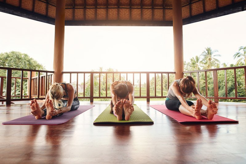 three-women-practicing-paschimottanasana-pose-at-y-P7F46KA.jpg